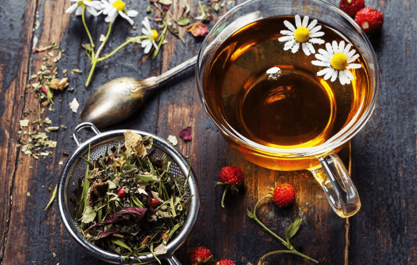 A cup of steaming herbal tea on a wooden table.